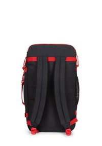 Czarny plecak z czerwonymi akcentami, posiadający wyściełane szelki, zamek błyskawiczny na górze oraz siatkową kieszonkę z boku. Gładka faktura materiału.