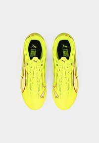 Bright yellow athletic shoes with a textured surface. Features include pink accents and Puma branding. Streamlined design with laces.