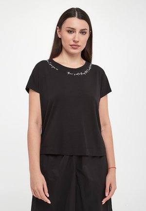 T-shirt noir à manches courtes avec un col rond et une coupe courte. Présente une broderie en texte blanc le long de l'encolure. Matériau en coton lisse.