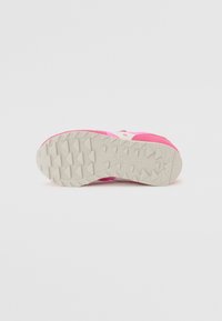 Chaussure de sport avec un dessus rose, dotée d'un logo blanc et d'une semelle en caoutchouc texturé avec un motif de crampons triangulaires pour l'adhérence.