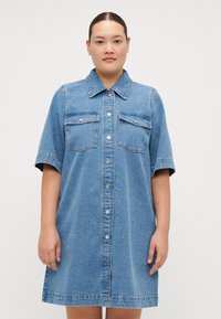Denim shirt dress with short sleeves, light blue color, front button closure, two chest pockets, and relaxed A-line silhouette.