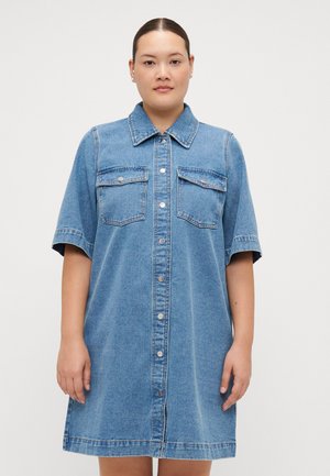 Denim skjortekjole med kort erme, lys blå farge, front knappestolpe, to brystlommer og en avslappet A-linje silhuett.