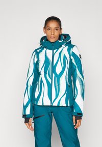 Sinine ja valge isoleeritud jakk lainemustriga, kõrge krae, reguleeritav kapuuts ja lukuga taskud; koos sobivate pükstega.