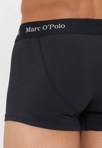 Schwarze Baumwoll-Boxershorts mit einem breiten elastischen Bund, der mit der Marke "Marc O'Polo" versehen ist. Weiche Textur mit einer figurbetonten Passform.