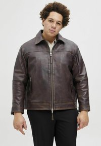 Brown leather jacket with a zip front, pointed collar, and side pockets. Features visible stitching and a smooth texture. Classic design.