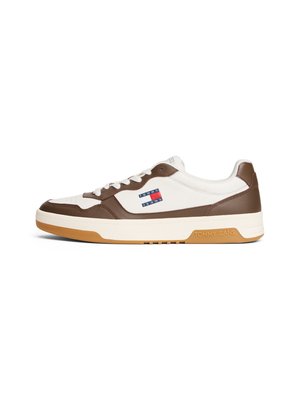 Baskets en cuir blanc et brun avec une semelle en caoutchouc couleur caramel, ornées d'un patch logo rouge, blanc et bleu sur le côté et d'accents bruns.