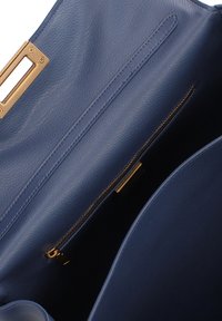 Interno di una borsa in pelle blu con una tasca con zip e dettagli in metallo dorato. Texture liscia, bordi arrotondati e senza motivi visibili.