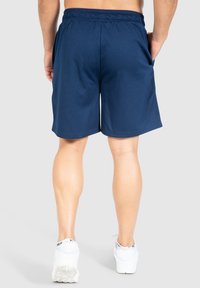 Pantalones cortos deportivos de color navy con una cinturilla elástica, tejido texturizado, bolsillos laterales y un corte holgado, que terminan justo por encima de la rodilla.