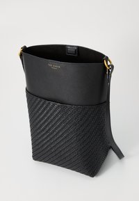 Saco cesto de pele preta com textura trançada na base, detalhes em metal dourado e uma parte superior lisa com o logo da marca.