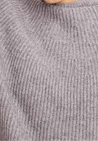 Maglione grigio a costine con collo alto, caratterizzato da una morbida texture e righe verticali sul tessuto.