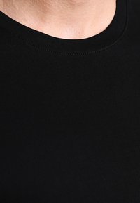 Sort bomulds T-shirt med rund halsudskæring. Har en glat tekstur og syninger omkring kraven. Ingen mønstre eller accenter synlige.
