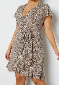 Beige šaty s leopardím vzorem, s krátkými volánkovými rukávy, zavazovacími boky a rozšířeným lemem s volánkovým detailem.