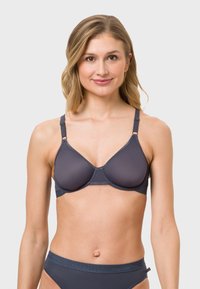 Gray bra with smooth fabric, molded cups, and adjustable straps. Features a seamless design and subtle stitching details.