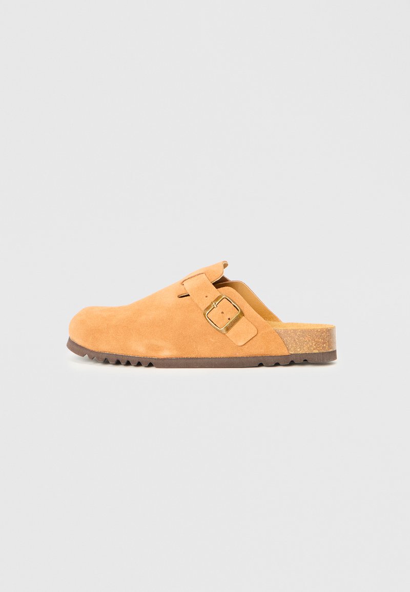 Beige Wildleder-Slipper mit verstellbarem Seitenverschluss und Korkfußbett, flache Gummisohle, seitlich auf einem einfarbigen Hintergrund präsentiert.