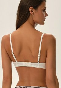 White bralette featuring adjustable straps, a smooth fabric finish, and a multi-hook back closure for customizable support.