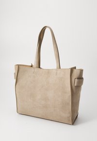 Sac fourre-tout en daim beige avec deux longues poignées, une forme structurée et des détails de couture subtils. Dispose d'accents latéraux pour une texture supplémentaire.