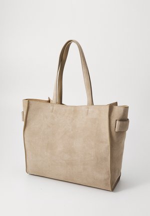 Sac fourre-tout en daim beige avec deux longues poignées, une forme structurée et des détails de couture subtils. Dispose d'accents latéraux pour une texture supplémentaire.