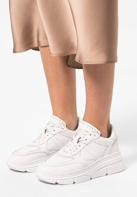 Witte sneakers van leer met gestructureerde accenten en dikke zolen. Het ontwerp heeft een ronde neus en gestikte details langs de bovenkant.