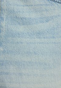 Tela de denim azul claro con una textura sutil y un patrón de sarga clásico. Presenta un ligero desgaste con líneas verticales visibles.
