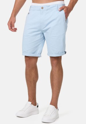Lichtblauwe katoen shorts met opgerolde mouwen, een enkele knoopsluiting en zijzakken. Gecombineerd met witte sneakers met een zwarte accenten.