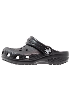 Zwarte klomp gemaakt van lichtgewicht materiaal met ventilatiegaten, verhoogde nopjes aan de buitenkant en een verstelbare hielband.