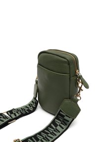 Sac en cuir texturé vert à bandoulière avec une fermeture éclair sur le dessus, doté d'une sangle réglable à motif et d'accents en métal doré.