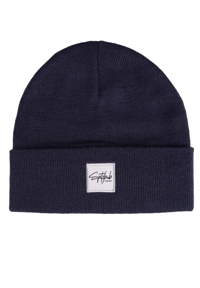 Navy knitted beanie hat with a folded cuff, featuring a white square label with black text on the front. Soft texture, flexible material.