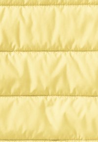 Tejido acolchado amarillo con una textura suave, que presenta costuras horizontales y un suave brillo. Un acolchado compacto crea una apariencia ligera.