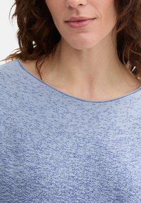 Helles blaues strukturiertes Oberteil mit weitem Ausschnitt. Verfügt über ein meliertes Muster, weichen Stoff und eine lockere Passform für zusätzlichen Komfort.