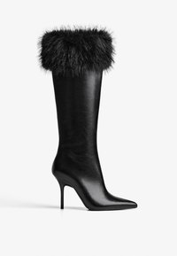 Čierne kožené boty po kolená s špicatou špičkou a ihličkovým podpätkom, s nadýchaným čiernym kožúškom na vrchu. Hladká textura po celom povrchu.