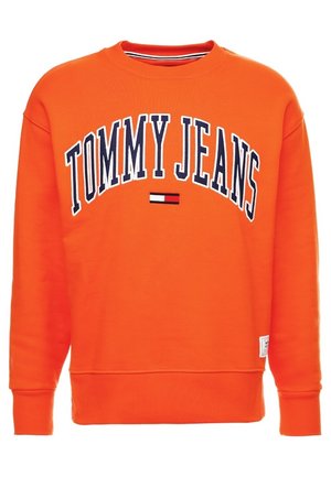Oranje sweatshirt met ronde hals met de tekst "TOMMY JEANS" in marineblauw en wit, met een klein rood, wit en zwart logo onder de tekst.