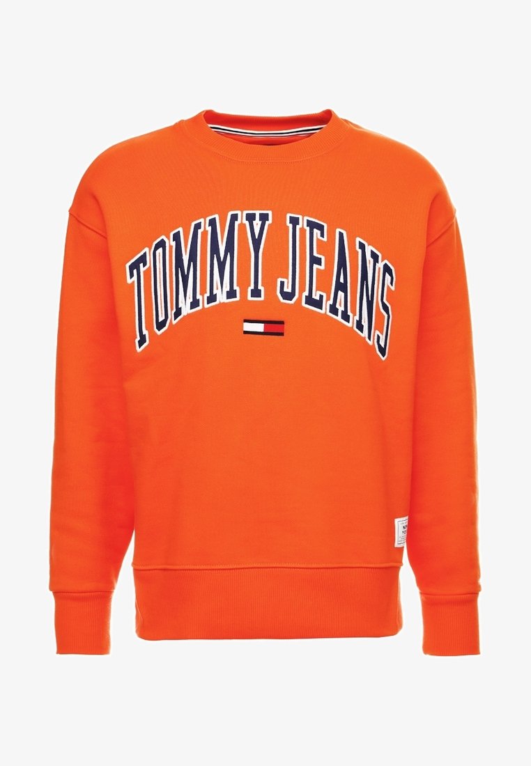Sweat-shirt orange à col rond avec le texte "TOMMY JEANS" en bleu marine et blanc, présentant un petit logo rouge, blanc et noir sous le texte.