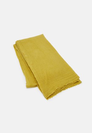 Écharpe en tissu jaune moutarde pliée, à la texture douce et aux bords légèrement effilochés, sur un fond blanc uni.