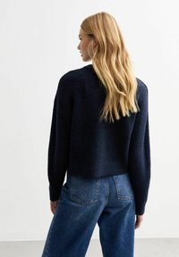 Blå, kort tröja gjord av strukturerat, fluffigt material. Kombinerad med högmidjade jeans som visar en avslappnad passform och rak ben-design.