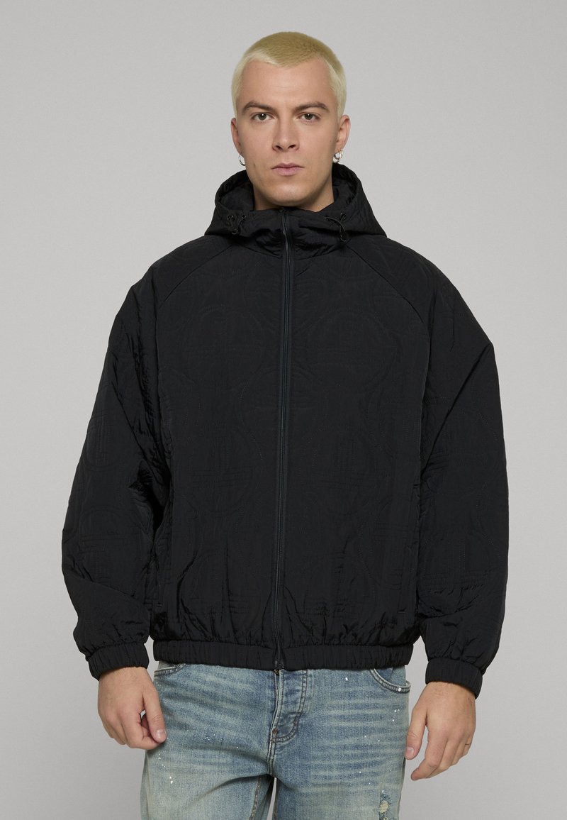 Giacca imbottita nera con cappuccio, dotata di chiusura con zip e polsini elastici, con un motivo tonale sottile e una vestibilità comoda.