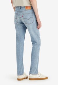 Ljusblå denimjeans med rak passform, synliga sömmar, två bakfickor och en märkesläderrande vid midjan.