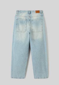 Jean en denim bleu clair avec une coupe décontractée. Présente une étiquette en cuir beige, deux poches arrière et une texture légèrement décolorée.