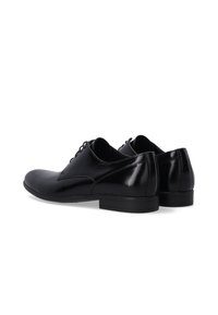 Zwarte leren dresschoenen met een gladde, glanzende afwerking. Kenmerken zijn een ronde neus, minimale stiksels en een lage, duurzame hak.