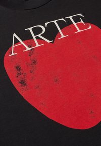 Zwarte T-shirt met een opvallende rode hartafbeelding met de tekst "ARTE" erboven, op een gestructureerde katoenen stof. Licht versleten details.