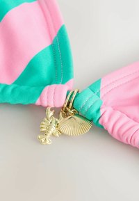 Tela a rayas coloridas en rosa y azul verdoso con un diseño anudado. Encantos dorados de langosta y concha sujetos al nudo. Textura suave y brillante.