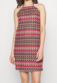 Robe à col halter présentant un motif en zigzag rouge, rose et noir. Fabriquée en tissu léger avec une silhouette ajustée.