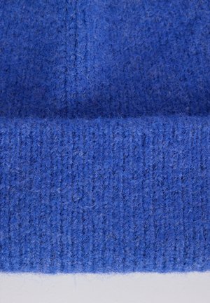 Gebreide blauwe beanie met een zachte, fuzzy textuur. Heeft ribbel-details en een omgeslagen rand, gemaakt van dik garen.