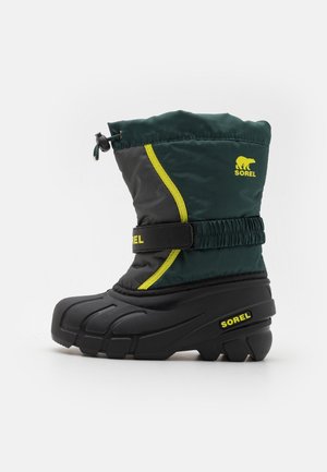 Botte d'hiver pour enfant en noir et vert foncé avec des accents jaunes, une sangle ajustable et une fermeture à cordon, arborant les logos Sorel.