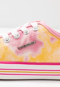 Baskets en toile avec un motif tie-dye rose, jaune et blanc ; dotées de lacets blancs, d'œillets argentés et d'une semelle rayée rose et jaune.