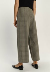 Plaid wide-leg trousers in textured fabric, featuring a neutral color palette with green and brown tones. Finished with a mid-rise waistband.