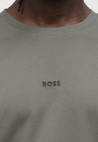 Πράσινο χακί T-shirt από ριμπ ύφασμα, με λαστιχένιο λογότυπο "BOSS" στην αριστερή πλευρά του στήθους. Κλασικός στρογγυλός λαιμός.
