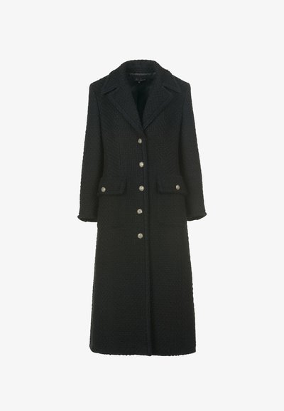 Musta teksturoitu villatakki pitkällä muotoilulla, hampailta leikatut läpät, kaksi etutaskua ja hopeiset koristepainikkeet edessä.