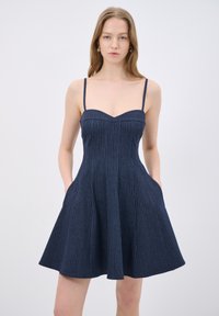 Sinsim vaale sinimustat raitapuku, jossa on istuva vartalokappale ja levenevä hame, sivutaskut ja sydänmainen pääntie.