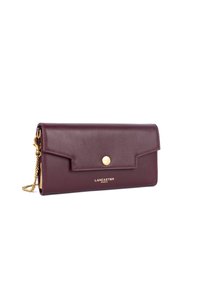 Portafoglio in pelle bordeaux con chiusura a patta, accessori in oro e tracolla a catena. Presenta un logo sul fronte e un design minimalista.