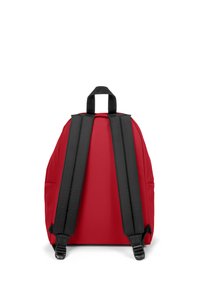 Red backpack with black padded straps and a top handle. Smooth fabric texture, rounded shape, no visible logos or patterns.